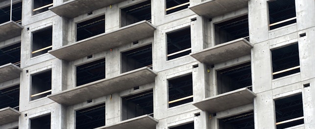 Na zdjęciu widoczny jest budynek w stanie surowym, z wieloma oknami, w trakcie budowy.